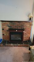 Full view of the electric fireplace insert set within a brick and stone hearth.