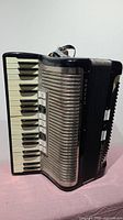 Front view of vintage black Hohner Contessa IVM accordion showing piano keys, silver grille, and white switches on the side.
