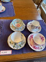 All four teacup and saucer pairs arranged on a purple placemat top view