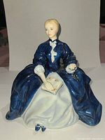 Front view of the Royal Doulton Laurianne figurine showing the seated woman in blue dress holding a floral book.
