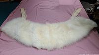 Full view of white fur stole collar laid flat on a surface with visible fur texture and attached fabric straps.