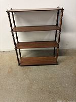 Front photo of the antique wooden four-shelf wall mount unit showing full frontal view of the shelves and turned spindle supports.