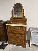 Front view of antique dresser showing attached mirror, drawers, and stone top.