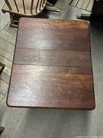 Top view of antique wooden drop-leaf table showing wood grain and surface wear including scratches and stains.