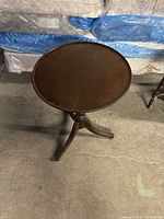 Top view showing round wooden tabletop with polished finish and some minor surface wear.