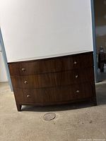 Front view of three-drawer bowfront dresser with brass knobs