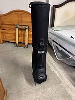 Side view of black rolling golf club bag standing upright in storage area.