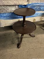 Front and side view of the mahogany two-tiered accent table showing round tops and pedestal design