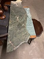 Full view of the polished green marble slab showing its irregular shape and polished surface, placed on a wooden surface.