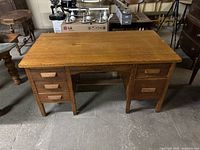 Full view of oak wood desk with six drawers, showing wood grain and satin finish.