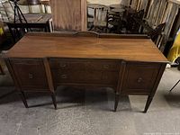 Front view of full wooden sideboard showing top surface, drawers, cabinets and legs