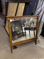 Full view of rectangular wooden framed dresser mirror with tilted glass, showing traditional style with side columns and medium wood finish.