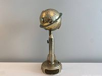 Front full view of the 1962 Duro Destination Moon Mechanical Bank showing the metallic rocket with moon globe and Saturn-like rings.