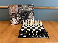 Chess set arranged on the chessboard with box in the background showing the set assembled with black and white Renaissance styled chess pieces.