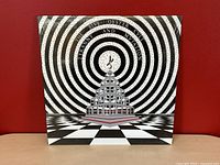 Front view of the Blue Öyster Cult "Tyranny And Mutation" album sleeve against a red background, showing the album artwork.