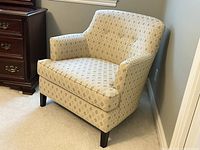 Beige upholstered Fauteuil Crapaud French armchair with patterned fabric, shown angled in room corner with dark wood legs.