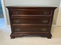 Front view of three-drawer mahogany dresser showing hardware and finish