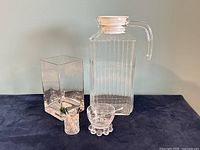 Overview of all four items including the glass pitcher, etched cruet bowl with spoon, glass vase, and plastic toothpick holder.