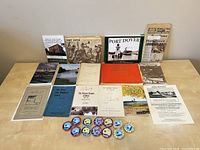 Full view of all books, documents, and pins laid out on a table with historical and event items related to Port Dover Ontario and Canada Day pins
