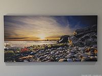 Close-up front view of the canvas print showing detailed beach sunset scene with rocks and ocean horizon.