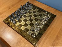 Angled view of full chess set on wooden table showing gold and silver pieces