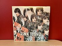 Front view of Pink Floyd The Piper at the Gates of Dawn album cover with psychedelic collage of band member faces.