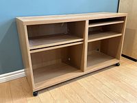 Front and side angled view of the wooden rolling credenza with open shelves and caster wheels on a hardwood floor.