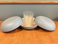 Three large Robins Egg Blue melamine salad serving bowls and five stacked clear plastic bowls on a wooden surface.