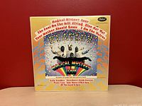 Front cover artwork of the Magical Mystery Tour album with psychedelic colorful design showing The Beatles in animal costumes.