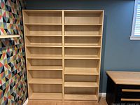 Front view of two oak finish IKEA BILLY bookshelves side by side, each with five shelves filled with nothing.