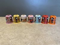 Front view of all 7 Noma Disney vintage metal Christmas light shades in a row showing the colorful designs and characters.