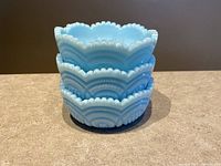 Three stacked blue satin glass bowls showing ruffled edges and textured pattern