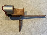 Side view of antique handheld stereoscope viewer showing wood handle and metal hood with felt lining.