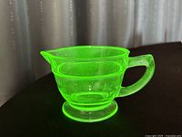 Green uranium glass measuring cup under normal lighting.
