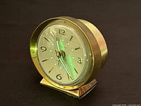 Vintage Baby Ben Westclox brass wind-up alarm clock shown from angled front view on dark surface.