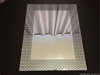 Full top-down view of mirror on black surface showing entire frame and reflective surface with curtain reflection