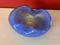 Full view of the purple-blue glass bowl showing its wavy rim and oval shape.