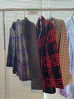 Four vintage jackets hanging on rack displaying various plaid and houndstooth patterns.