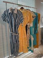 Front view of all six vintage midi dresses on rack, showing colors and patterns.