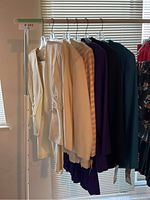 Six vintage skirt suits hung on a rack, colors include cream, purple, blue, and teal