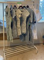 Full view of the seven rompers hanging on a rack showing varying styles and colors including light blue, gray, acid wash, and white