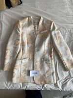 Full front view of Calvin Klein metallic floral blazer laid flat on surface showing pattern and structure.