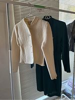 Front and side view of the cream wool jacket with ribbed knit details hanging next to the dress.