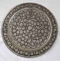 Full view of round Moroccan metal serving platter showing entire etched bird and floral pattern with outer floral border.