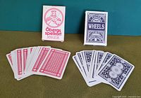 Two decks of vintage playing cards, Swedish Öbergs spelkort on the left and Austrian Platinum Wheels on the right, both with several cards fanned out to show front and back designs.