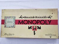 Yellowed, slightly stained and worn box cover with Monopoly branding and artwork.