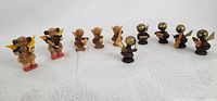 Photo showing the full set of 10 tiny wooden angels playing various musical instruments on a white background.