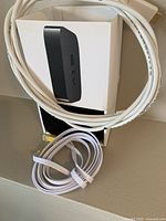Apple TV device, white HDMI cable and power cord packed in the original box.