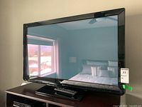 Full view of the Panasonic flat-screen TV placed on a wooden surface in a bedroom setting.