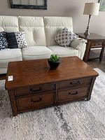 Wooden coffee table with closed top showing 4 front drawers and additional storage below.